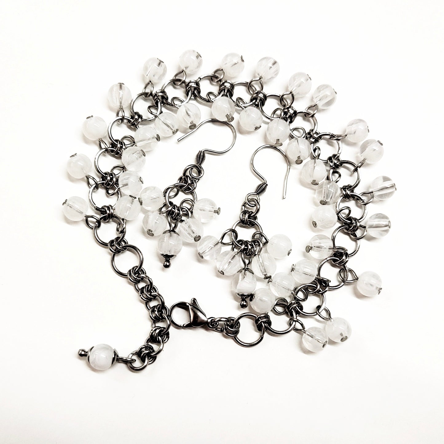 A set of clear and white beads bracelet and dangling earrings